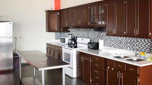 a kitchen with wooden cabinets and a white stove top oven at Quinta Sunset, Lago de Coatepeque in El Congo