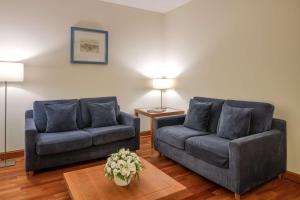 una sala de estar con 2 sofás azules y una mesa. en NH Marbella, en Marbella