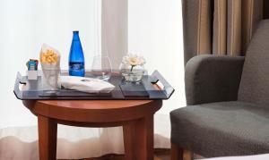 a table with a bottle and glasses and a chair at NH Marbella in Marbella