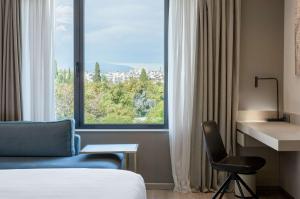 a hotel room with a bed and a desk and a window at Radisson Blu Park Hotel Athens in Athens