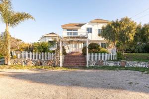 a white house with a fence and a palm tree at Malibu Coastal Romantic Getaway, Beach & Hike Nearby in Malibu