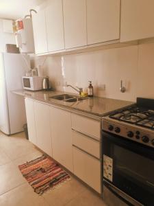 a kitchen with white cabinets and a sink and a stove at Excelente Apartamento Centro Opcional Cochera by Lofter in La Plata