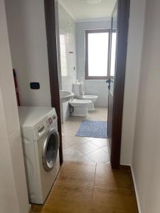ein Badezimmer mit einer Waschmaschine und einem WC in der Unterkunft Ajla’s home in Vorë