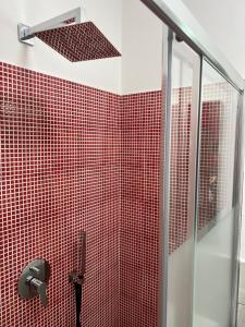 uma casa de banho com paredes em azulejos vermelhos e um chuveiro em Alì Babà Rooms em La Spezia