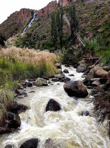 a river with rocks and a waterfall in a mountain at Cabaña La Rinconada Cayara in Potosí