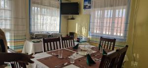 a dining room with a table and chairs and a television at Frankfurt Cottages in Mbale