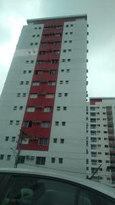 un edificio alto rojo y blanco con un coche delante en Apartmento Condominio Paradise Lake Dom Pedro, en Manaus