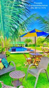 a picnic table and chairs with an umbrella and a pool at Pousada Areias de Flecheiras in Flecheiras