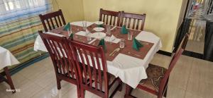 einen Esstisch mit einem weißen Tischtuch und Stühlen in der Unterkunft Frankfurt Cottages in Mbale