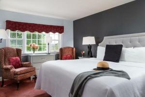 um quarto com uma grande cama branca e 2 cadeiras em Rabbit Hill Inn em Lower Waterford