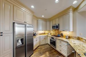 a kitchen with white cabinets and a stainless steel refrigerator at Lagoon Sunrise 205 in Carlsbad