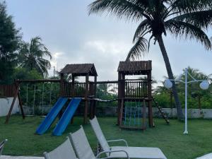 a playground with a slide and a swing set at Itacimirim Summer Ville - Pé na Areia in Itacimirim