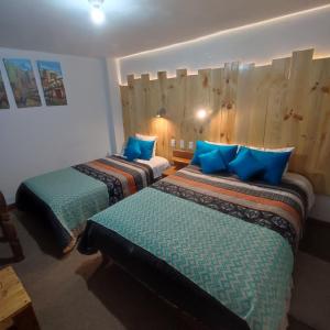 2 camas en una habitación con almohadas azules en CASA SAPANTIANA con vista al bosque, cerca a Sacsayhuaman en Cusco