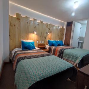 Habitación de hotel con 2 camas y almohadas azules en CASA SAPANTIANA con vista al bosque, cerca a Sacsayhuaman en Cusco
