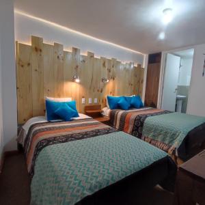 Habitación de hotel con 2 camas y almohadas azules en CASA SAPANTIANA con vista al bosque, cerca a Sacsayhuaman en Cusco