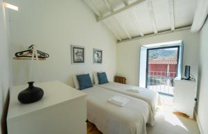 a white bedroom with two beds and a window at Casas de Vila Pouca in Mondim de Basto +67 photos