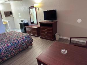 ein Hotelzimmer mit einem Bett und einem Flachbild-TV in der Unterkunft CRYSTAL MOTEL in Tulsa