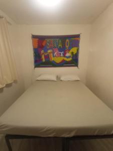 uma cama num pequeno quarto com uma almofada na parede em Apartamento da sereia itapua em Salvador