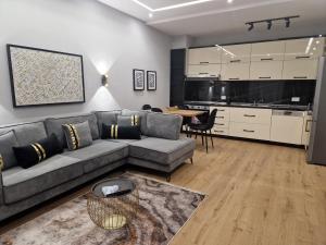 ein Wohnzimmer mit einem grauen Sofa und einem Tisch in der Unterkunft Deluxe Rent Apartment in Tirana