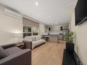 a living room with a couch and a kitchen at Central Shepparton Apartments in Shepparton