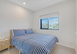 a bedroom with a striped bed and a window at Sunny Gold Coast Miami Getaway in Gold Coast