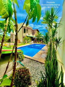 a swimming pool in front of a house with palm trees at Pousada Areias de Flecheiras in Flecheiras