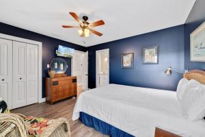 a blue bedroom with a bed and a ceiling fan at Walk to Beach, Secluded, Gazebo with Grill, 1GiG WiFi, Washer and Dryer, Games in Gulf Shores