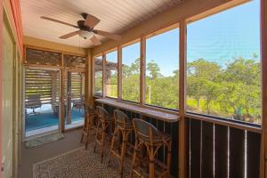 a screened in porch with chairs and a ceiling fan at Walk to Beach, Secluded, Gazebo with Grill, 1GiG WiFi, Washer and Dryer, Games in Gulf Shores