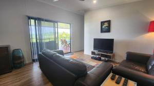 sala de estar con sofá y TV de pantalla plana en Bedarra Beachhouse, en South Mission Beach