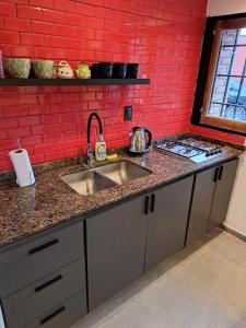 a kitchen with a sink and a red brick wall at Departamento Entero 2 Dormitorios B° Urca con Cochera in Cordoba