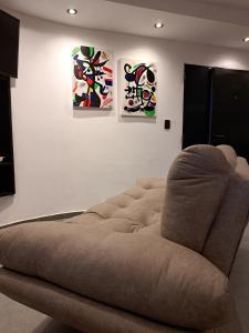 a brown couch in a room with three paintings at Departamento Entero 2 Dormitorios B° Urca con Cochera in Cordoba