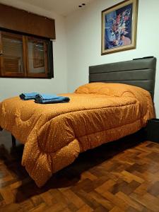 a bedroom with a bed with an orange blanket at Departamento Entero 2 Dormitorios B° Urca con Cochera in Cordoba