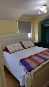 Un dormitorio con una cama blanca con almohadas y una ventana en Habitación 1 casa/tinaja/piscina, en Valdivia