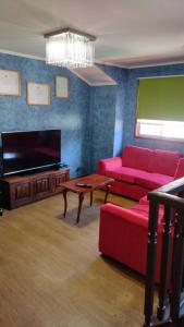 sala de estar con sofá rojo y TV de pantalla plana en Habitación 1 casa/tinaja/piscina, en Valdivia