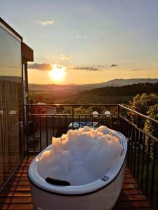 a bath tub sitting on a balcony with the sunset at Tiny House Paraiso Minicasas Com Hidromassagem in Pouso Alegre