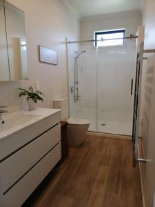 a bathroom with a shower and a sink and a toilet at Purangi Beachhouse in Cooks Beach