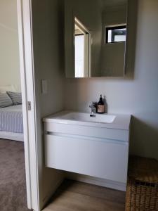 a bathroom with a white sink and a mirror at Purangi Beachhouse in Cooks Beach