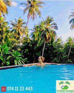 a woman in a swimming pool in front of palm trees at The Hideaway in Kurunegala