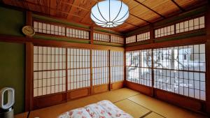 Habitación con ventanas, cama y reloj en 富士吉田かつまたや en Fujiyoshida