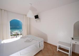 biała sypialnia z łóżkiem i oknem w obiekcie Seaview Rooms w mieście Vasiliki