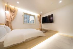 a bedroom with a white bed and a television at The Hyoosik Nomad Aank Hotel Gumi in Gumi