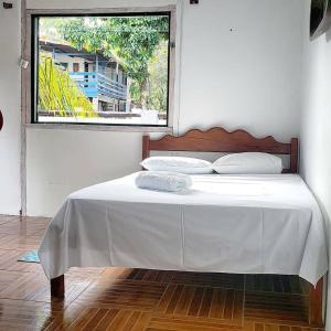 a bedroom with a white bed with a window at Pousada Boto in Salvaterra