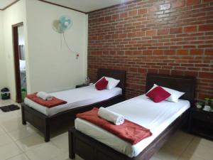 two beds in a room with a brick wall at Penginapan Homestay Mudiyono Syari'ah in Borobudur