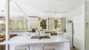 a white kitchen with a sink and a refrigerator at Tea Tree House - Pearl Beach in Pearl Beach