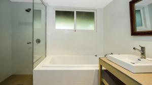 a white bathroom with a tub and a sink at Beach Vista - A Designer Delight Oposite The Beach in Pearl Beach