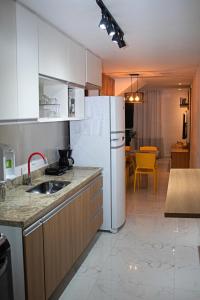 a kitchen with a sink and a white refrigerator at Luxo com Spa exclusivo no paraíso do Peró! in Cabo Frio +66 photos