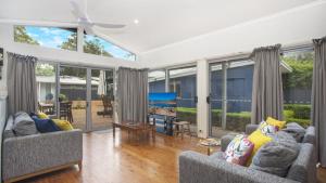 a living room with two couches and large windows at Pippi Rikki - Pearl Beach With Wifi in Pearl Beach