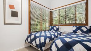 two beds in a room with a window at Pearl Beach Quarterdeck in Pearl Beach