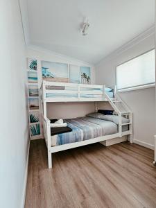 a bedroom with white bunk beds in a room at 2 Min Walk to Beach Firepit Yard Kids welcome in Ettalong Beach