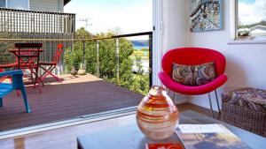 Il comprend un salon avec une chaise rouge et un balcon. dans l'établissement Patonga Corner Creek - Water Glimpses, à Patonga Beach